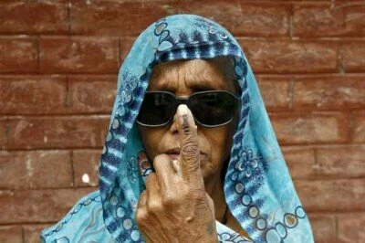 A woman shows her ink-marked finger after casting her vote at Makum village